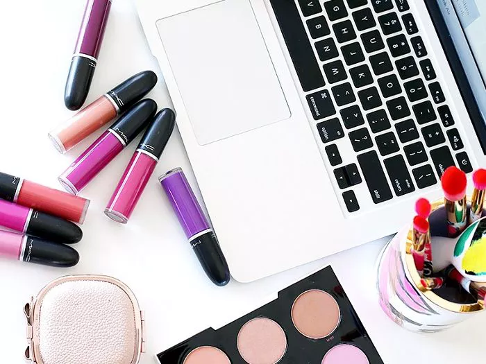 Laptop with liquid lipstick and makeup brushes