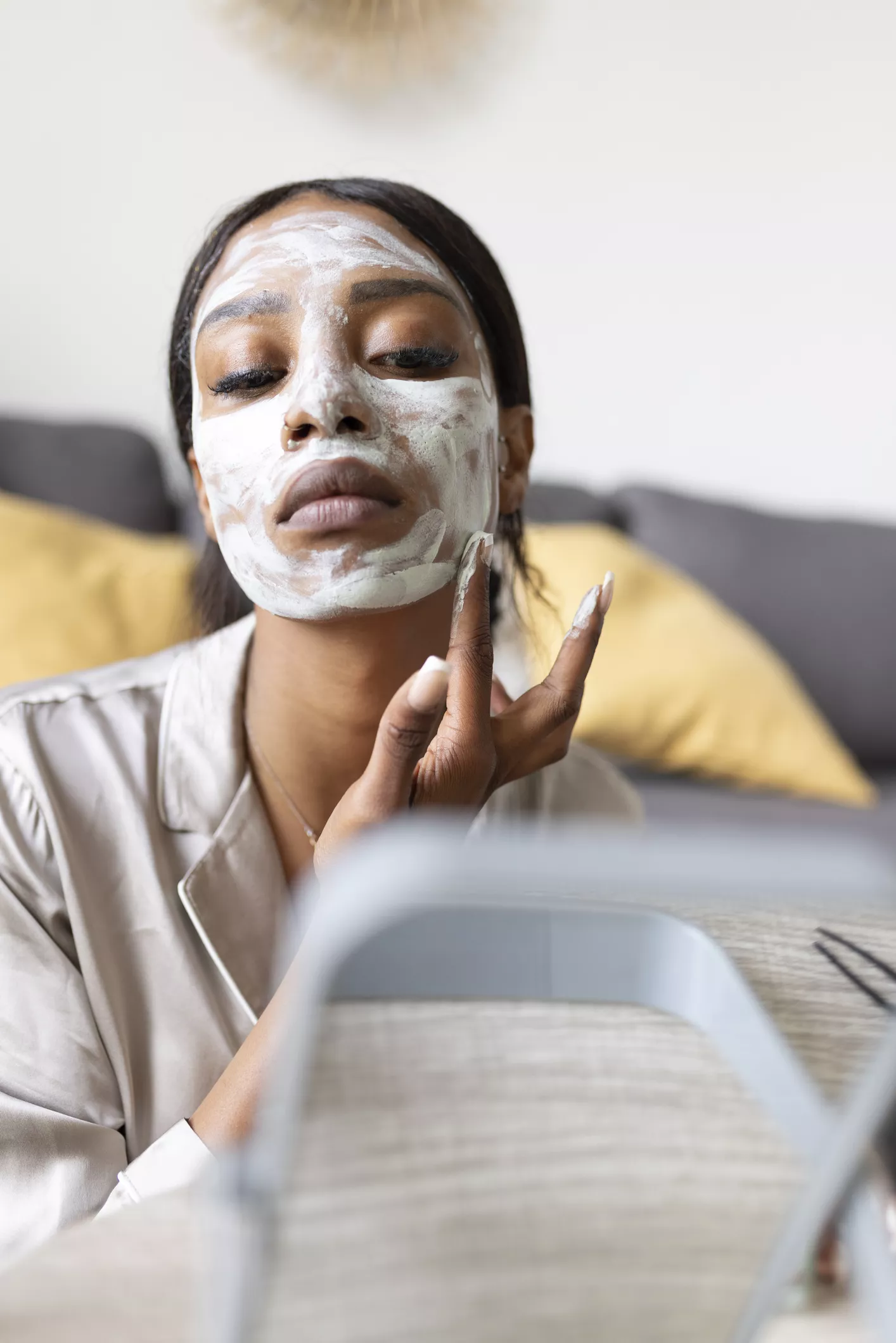 Woman applying face mask in front of mirror