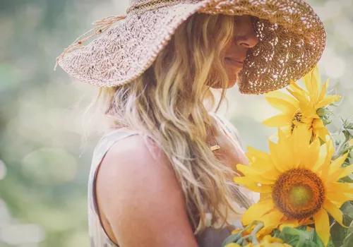 Blonde woman with a sun hat and sunflowers