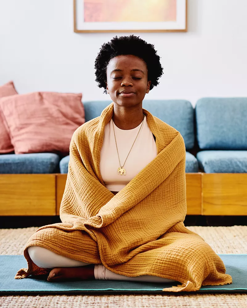 black femme meditating on yoga mat