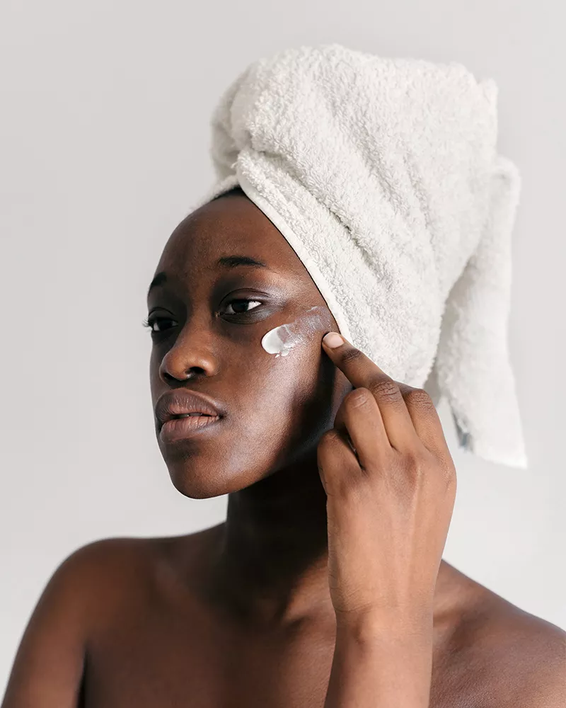 black femme applying face lotion
