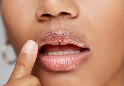 woman touches her glossy lips