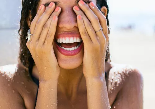 woman smiling taking a shower on the beach