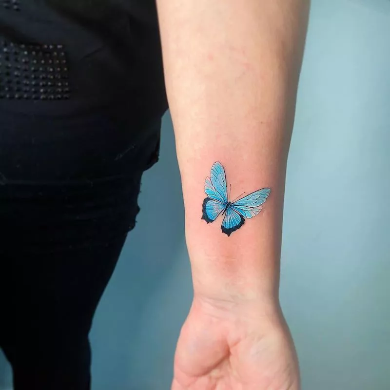 Dynamic blue butterfly tattoo on forearm