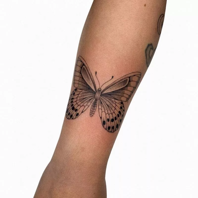 Realistic blackwork butterfly tattoo on forearm