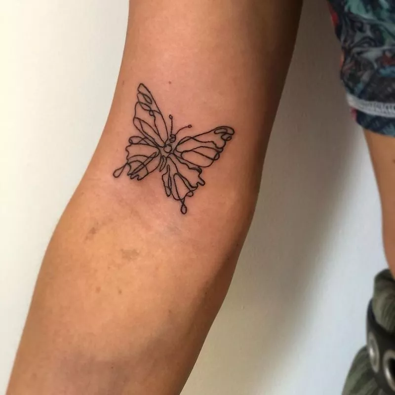 Line art butterfly tattoo on inner elbow
