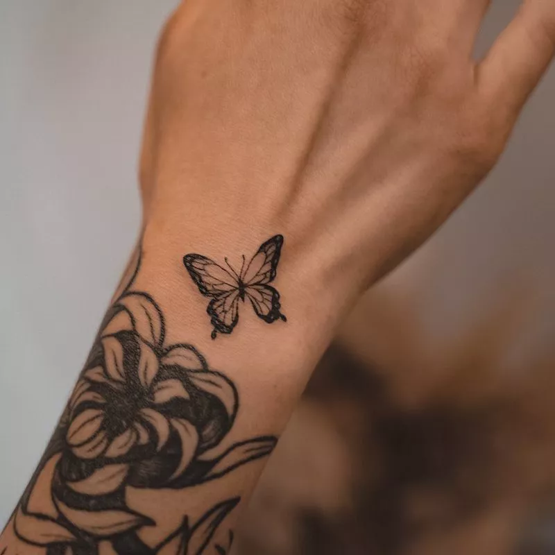 Wrist sleeve tattoo with butterfly near hand