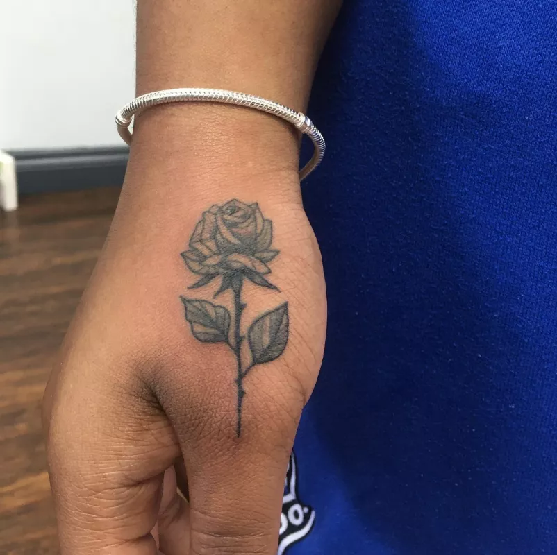 Rose tattoo on side of thumb
