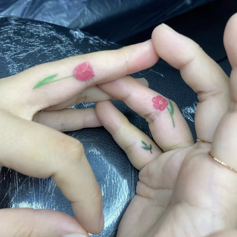 Red and green flower finger tattoos