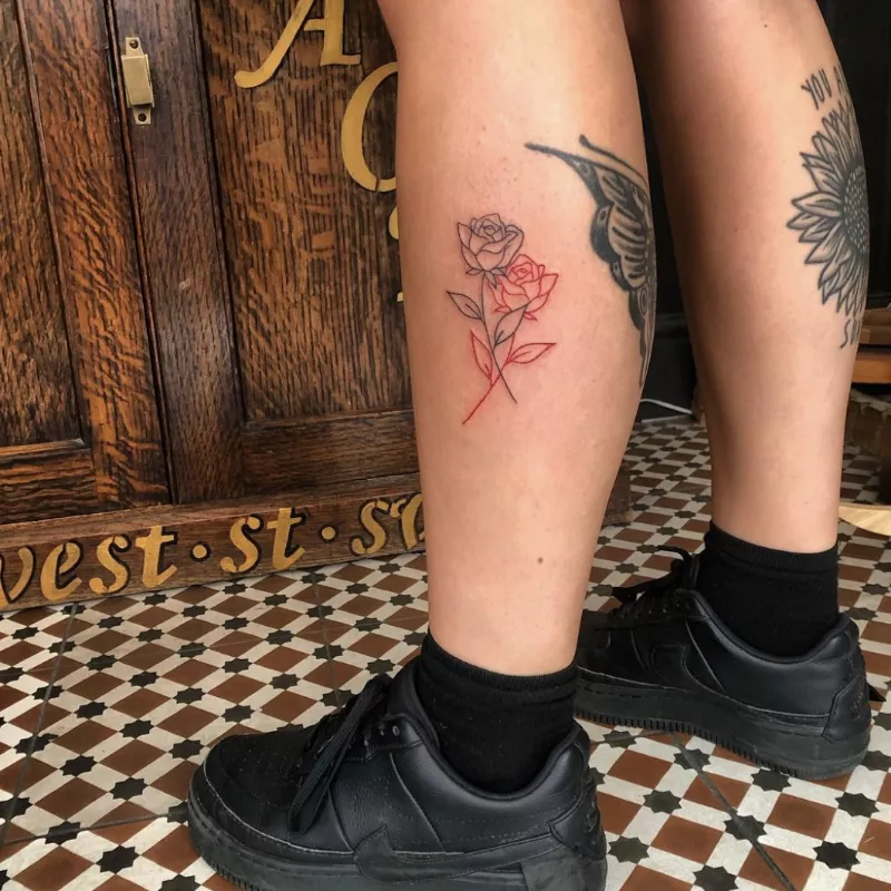 calf tattoo of intertwined black and red rose