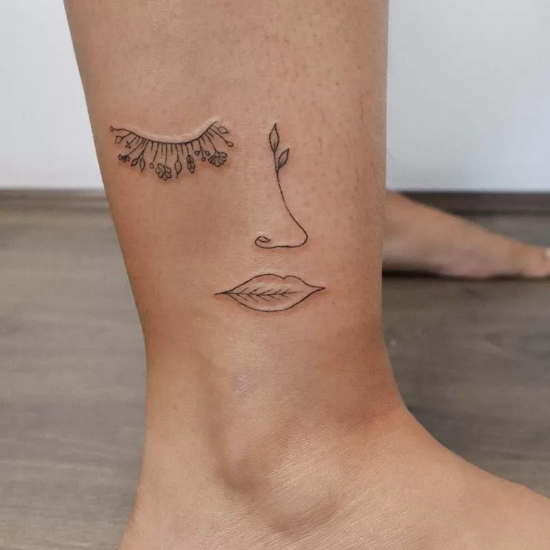 Ankle tattoo of a face made of leaves