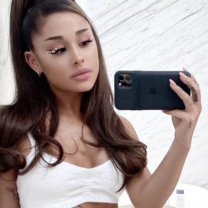 Ariana Grande poses for a mirror selfie with finger tattoo and floral lashes