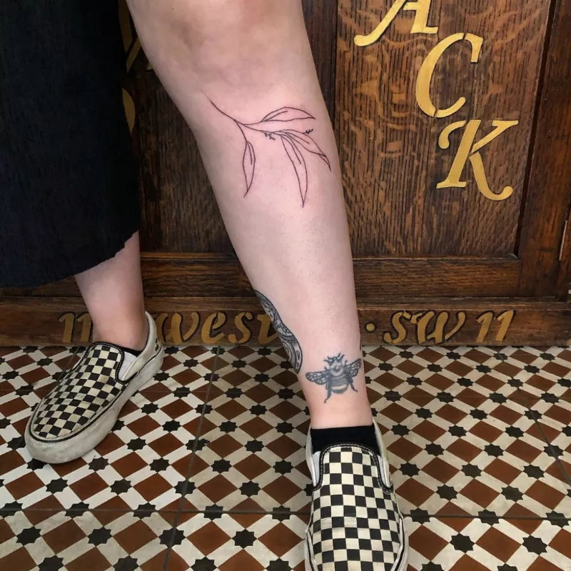 Leafy branch tattoo on shin below knee