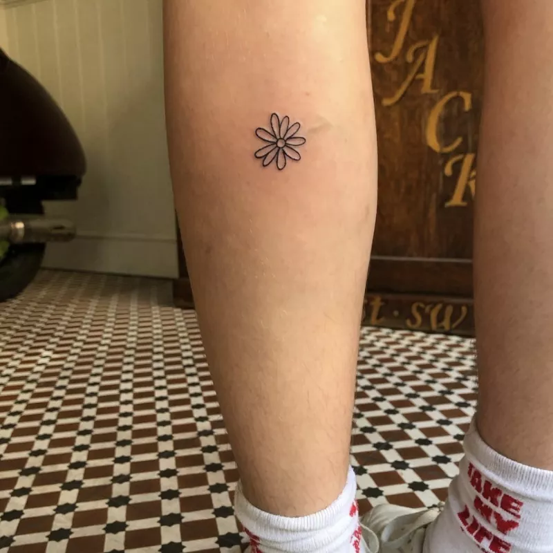 Small outline daisy tattoo on calf