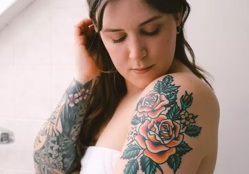 woman with arm tattoos standing in bathroom