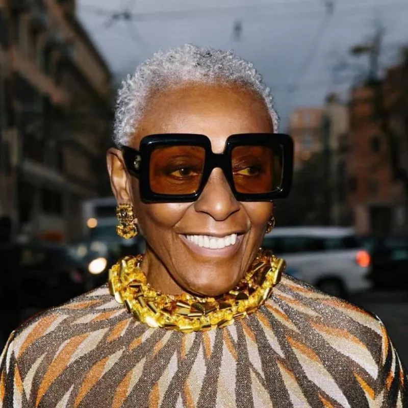 Bethann Hardison wears a short gray Afro hairstyle and large square sunglasses