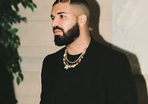 Drake wears a thick, full beard and short hairstyle