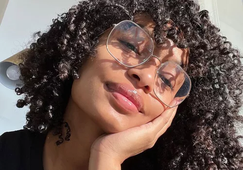 Yara Shahidi wears large wire glasses and her natural type 3C curly hair