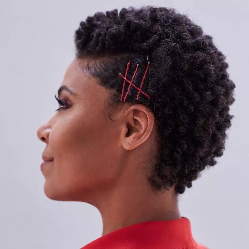 Sanaa Lathan wears a short afro hairstyle with red bobby pins