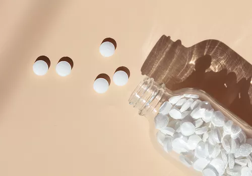 Biotin supplements scattered on a peach colored background.