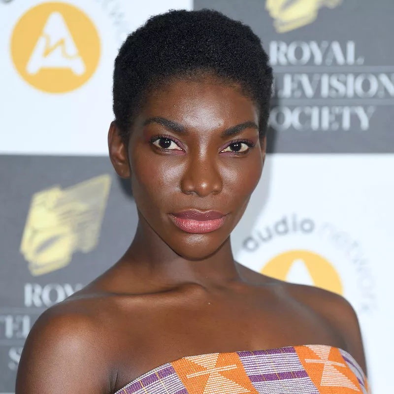 Michaela Coel wears a tapered short Afro hairstyle and natural makeup