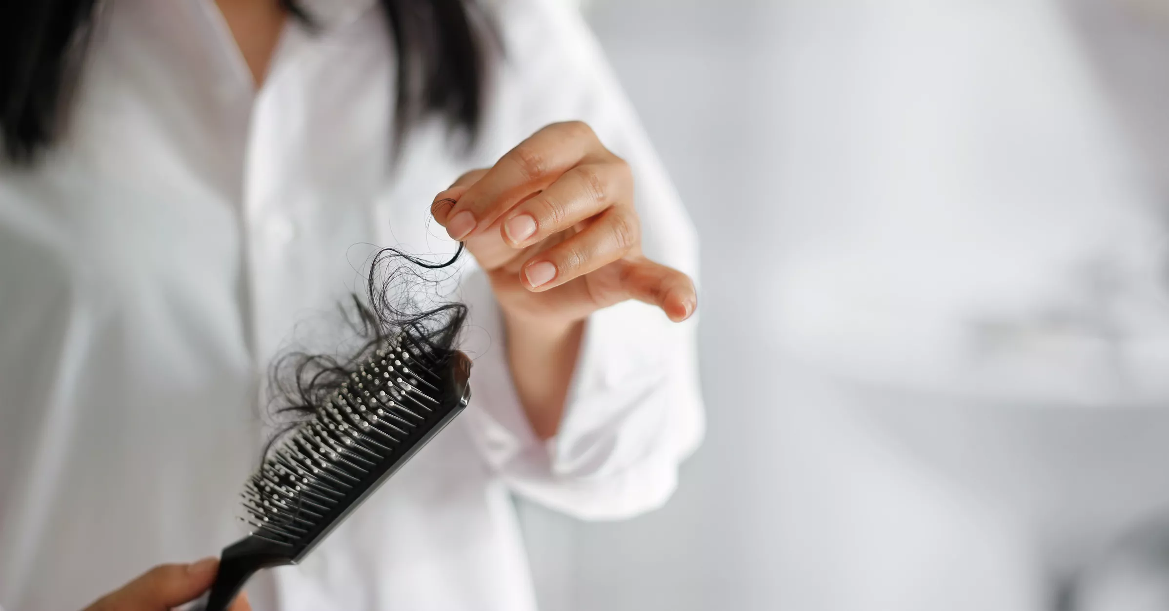 woman losing hair on hairbrush in hand 