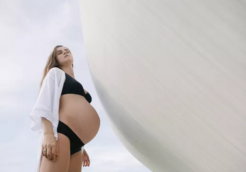 Pregnant woman looks up towards the sun