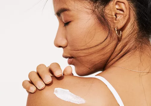 woman applying sunscreen on shoulder