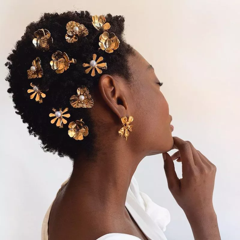 Side of woman's short natural hairstyle with multiple gold floral hair clips