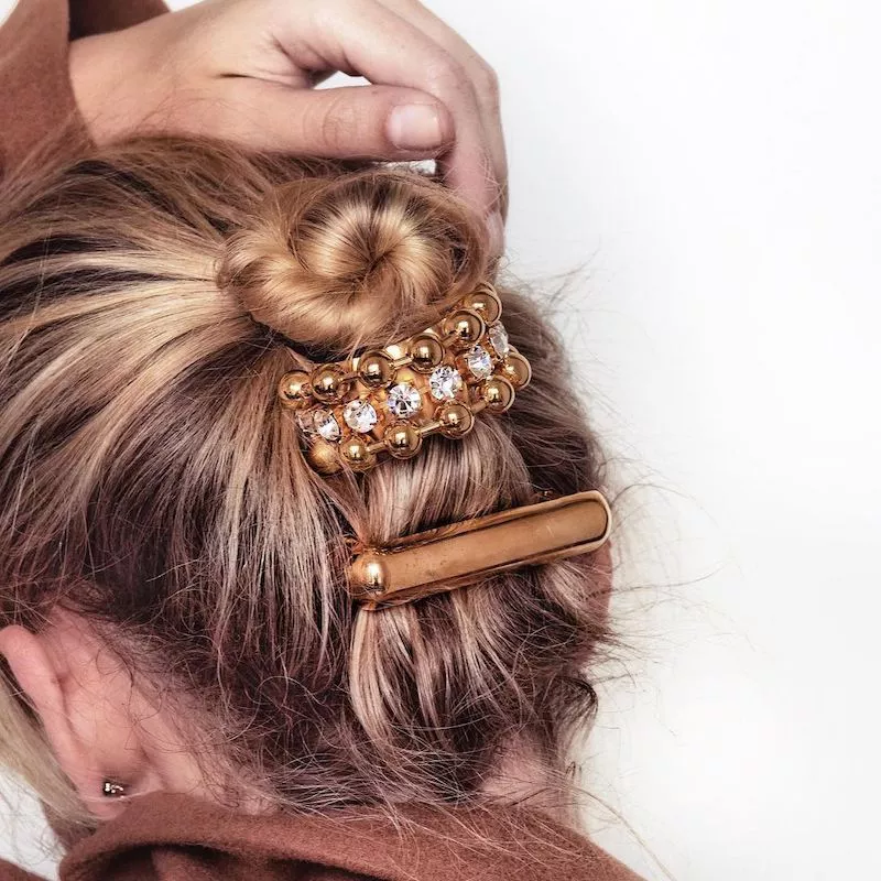 Back of blonde woman's updo hairstyle with adorned gold clips