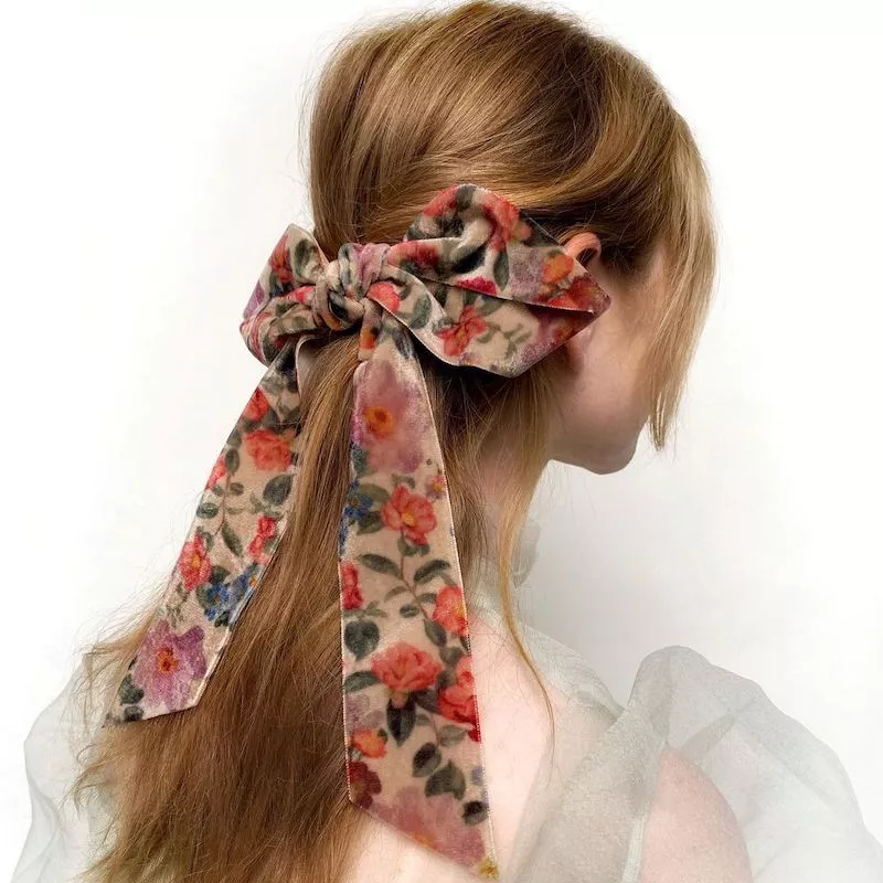 Back of half-up blonde hairstyle with floral patterned velvet bow