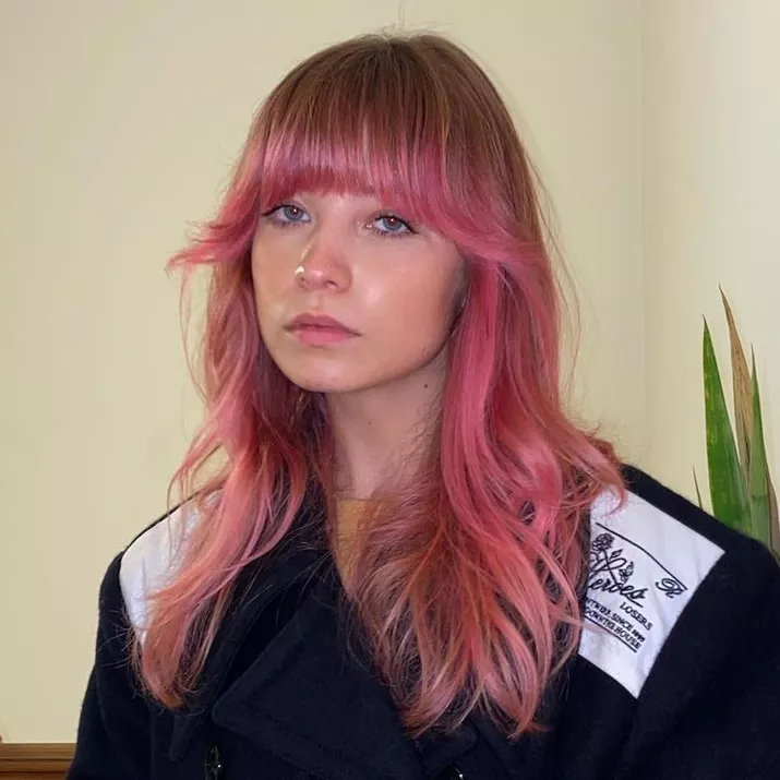 Woman wears pink ombre hair with flared '70s bangs