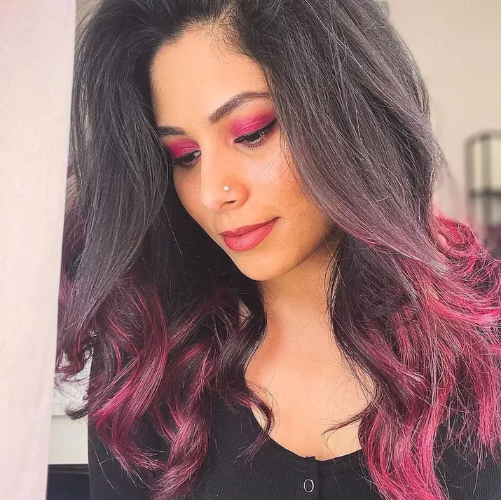 Woman with tousled dark hair with pink ombre tips and eyeshadow