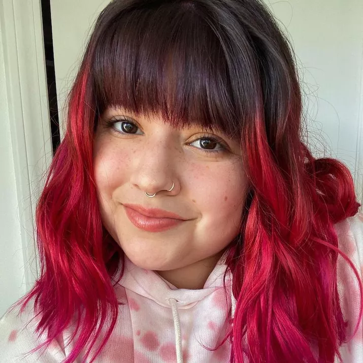 Woman with pink ombre hair and natural dark bangs