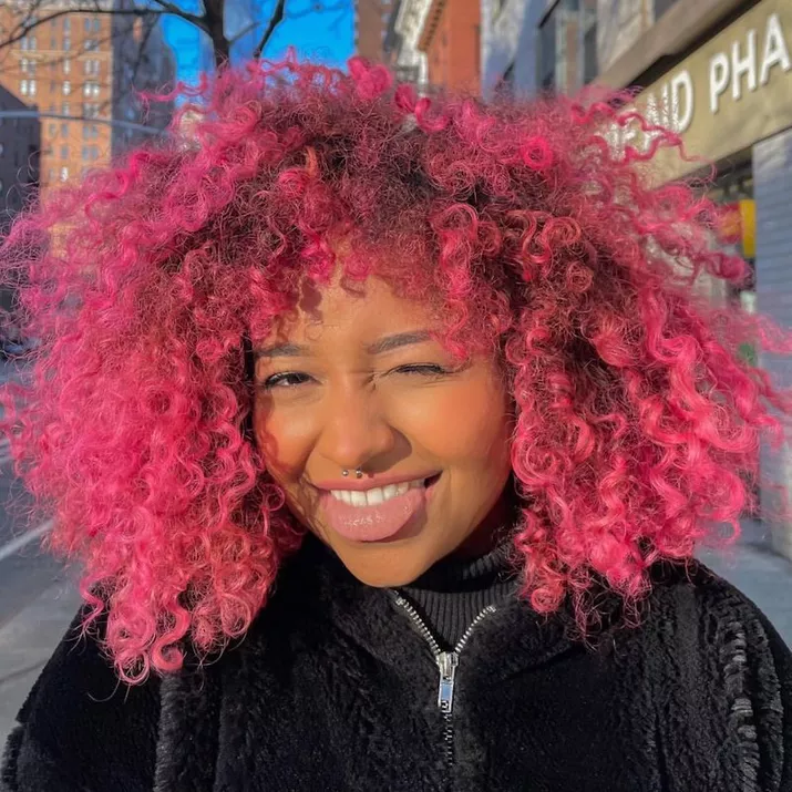 Woman wears vibrant magenta ombre natural curls
