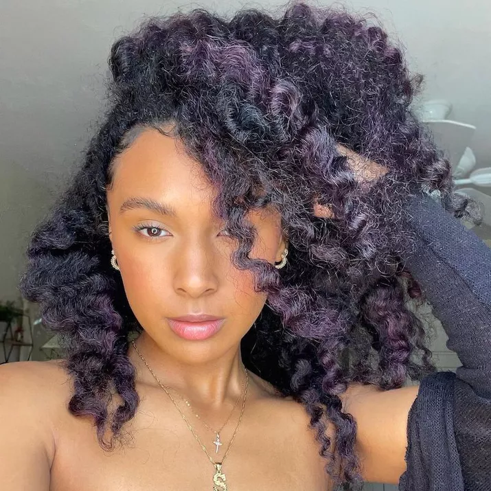 Woman with naturally curly hair with deep purple highlights