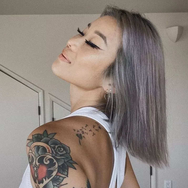 Woman with a pastel lavender bob hairstyle and shoulder tattoos