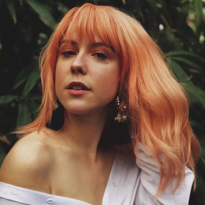 Woman wears a pastel peach hairstyle with bangs