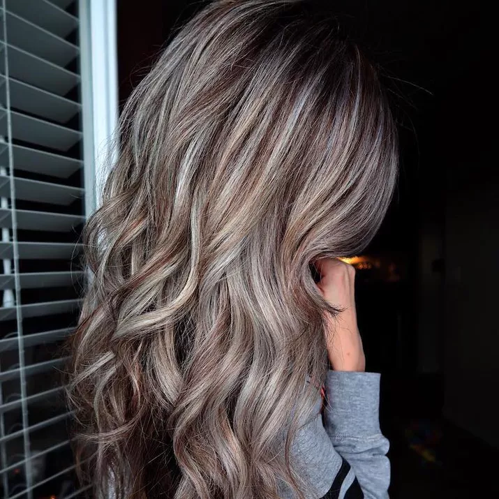 Side of long, curled brunette hairstyle with subtle silver highlights