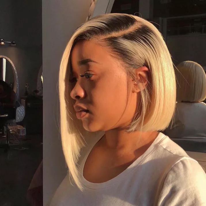 Woman wears a platinum asymmetrical bob with natural dark roots
