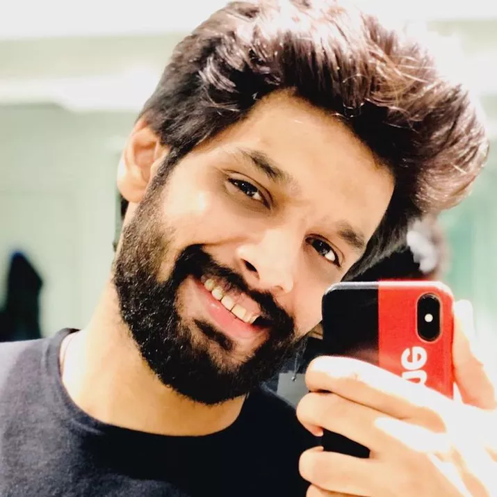 Man with tousled pompadour hairstyle and full beard taking mirror selfie