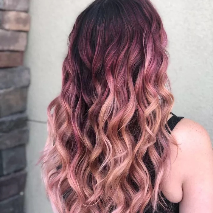 Rose gold balayage hair with dark roots, viewed from back