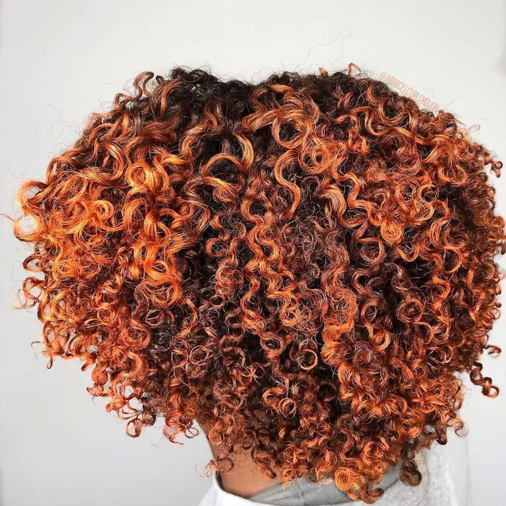 Natural curls with vibrant red-bronze highlights