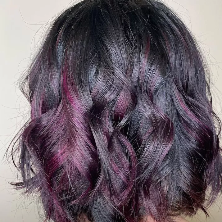 Angled, curled bob with purple highlights