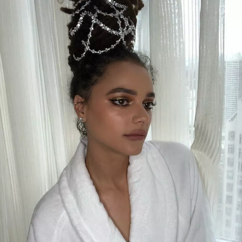 Sasha Lane wears an intricate updo with silver hair accessories