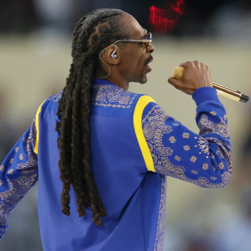 Snoop Dogg wears his signature dreadlocks and a blue paisley shirt