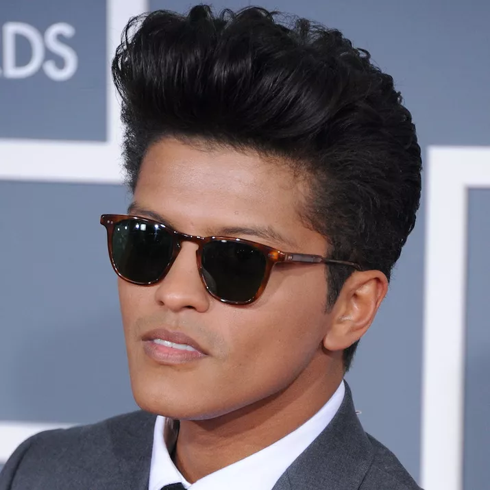 Bruno Mars wears a voluminous 1950s-inspired pompadour hairstyle and sunglasses