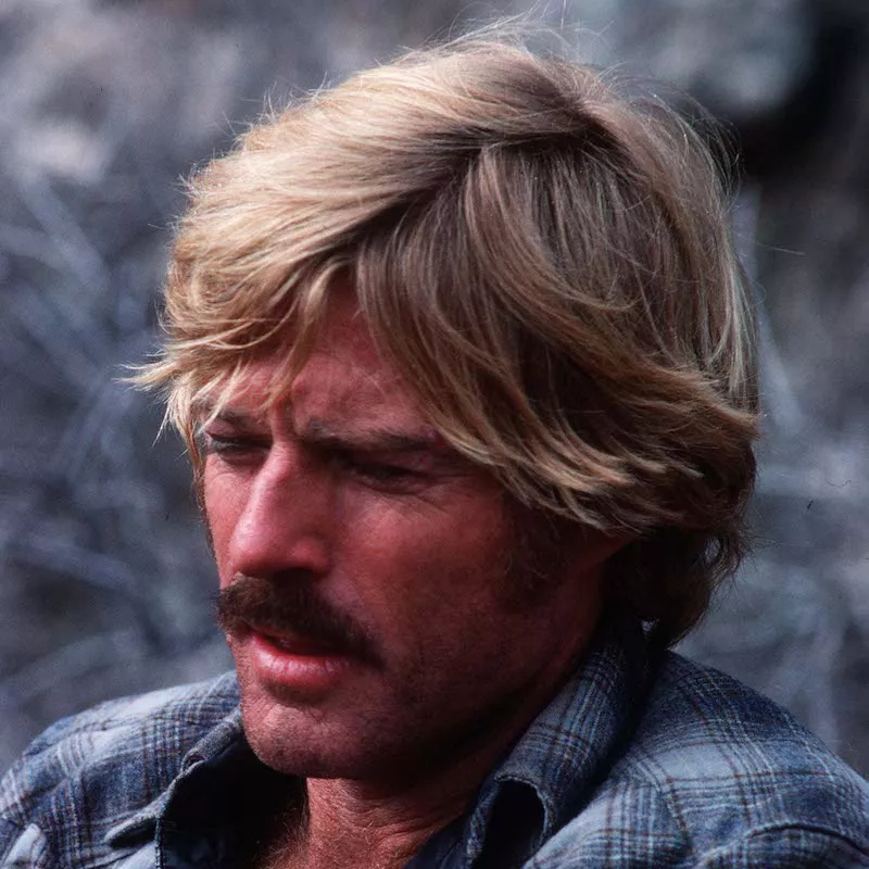 Robert Redford wears a short, tousled hairstyle on a 1979 movie set