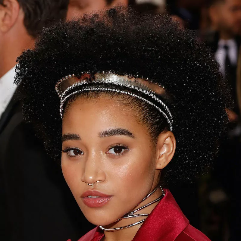 Amandla Stenberg wears a curly Afro hairstyle with golden and bedazzled headbands