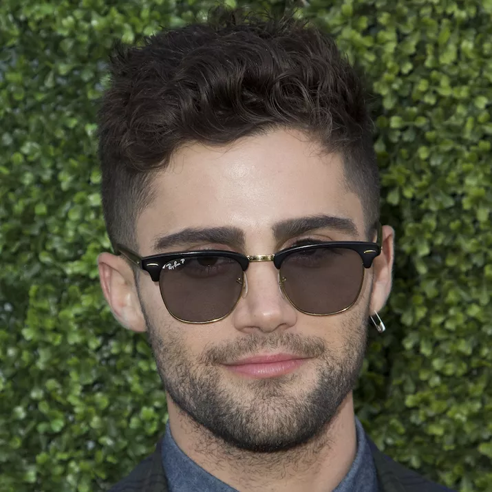 Max Ehrich wears a textured hairstyle with undercut and beard